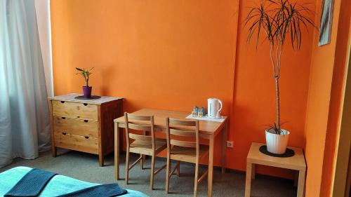 una mesa y sillas en una habitación con una pared de color naranja en Motel Grádo, en Praga