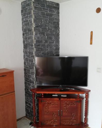 a television on a stand in front of a brick fireplace at Къща Томови,стаи за гости in Devin