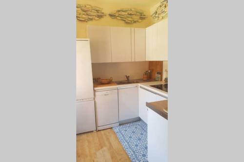 une cuisine avec des placards blancs et un tapis bleu dans l'établissement C069-Magnifique appartement au coeur du suquet, à Cannes