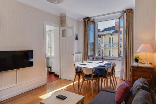 a living room with a table with chairs and a tv at Annecy Triangle d'Or - 3 bedroom apartment in Annecy