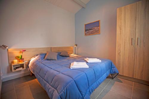 ein Schlafzimmer mit einem blauen Bett und Handtüchern darauf in der Unterkunft Village Vacances Passion Les Bris in Saint-Trojan-les-Bains