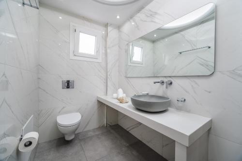 a white bathroom with a sink and a toilet at Stavros Villas in Karterados