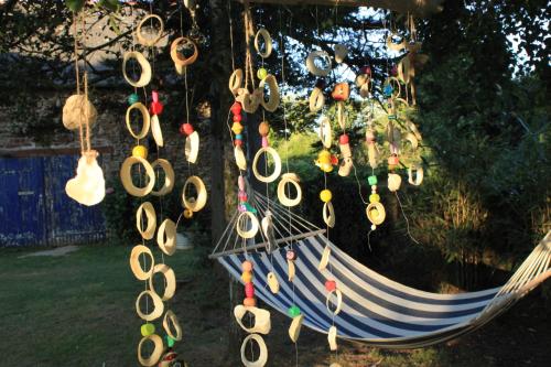 a hammock with hats and other items hanging from it at Chambre d'hôtes Suite 53m2 ou Caravane vintage avec cuisine et salle de bains privées, B&B 53m2 Suite or Vintage caravan with private kitchen and bathroom in Pleumeur-Gautier