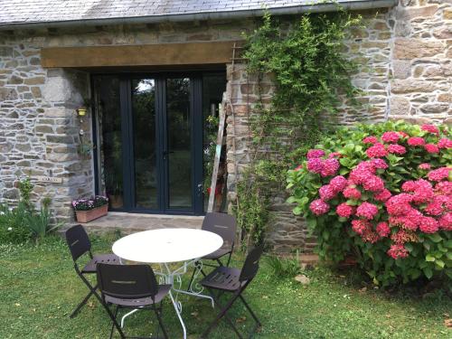 einen Tisch und Stühle vor einem Haus mit Blumen in der Unterkunft B&B Chambre d'hôtes et Glamping, Bretagne mer et campagne Brittany sea and countryside in Pleumeur-Gautier