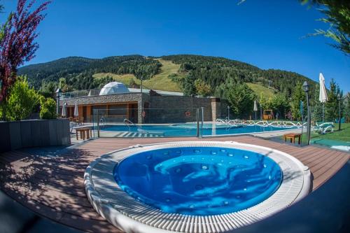 a large swimming pool with a house and a building at Hotel Nordic in El Tarter
