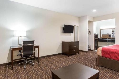a hotel room with a bed and a desk and a bed and a chair at Scottish Inns & Suites Spring - Houston North in Spring