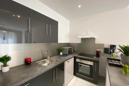 a kitchen with a sink and a stove at Le Sunshine - Terrasse et clim in Nîmes