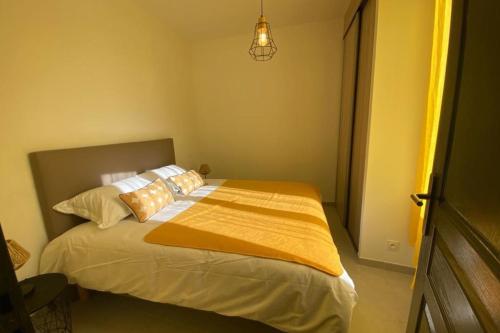 une chambre avec un lit avec des draps et des oreillers jaunes dans l'établissement Le Sunshine - Terrasse et clim, à Nîmes