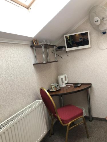 a desk with a chair and a tv on a wall at Motel Kurortnyy & SPA in Shklo