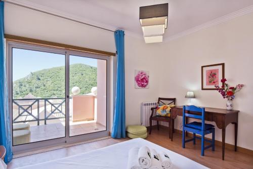 a room with a bed and a desk and a window at BmyGuest - Sesimbra Sea View Villa in Castelo