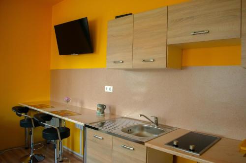a kitchen with a sink and a counter with stools at Mónika Vendégház in Mórahalom