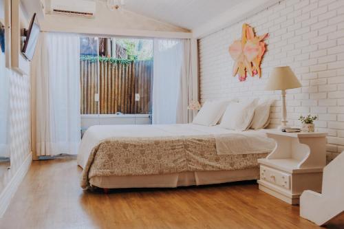 a white bedroom with a large bed and a window at Chez Louise et Louis Pé na Areia in Juquei