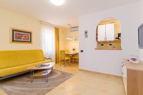a living room with a yellow couch and a table at Apartments Fiorido in Medulin