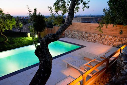 a swimming pool with a tree in front of it at Quinta do Tio Viagem in Quinta do Anjo