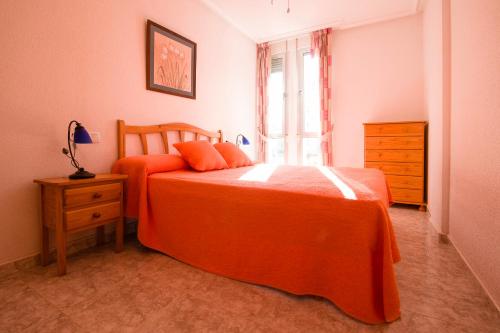 グアルダマル・デル・セグラにあるApartamento Playa 2 habitaciones parkingのベッドルーム1室(オレンジ色のベッド1台、窓付)