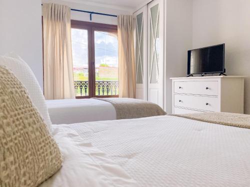 a bedroom with two beds and a tv and a window at Villaprado in Cambados