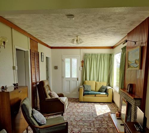 uma sala de estar com duas cadeiras e um sofá em The Bungalow Self-catering Accommodation em Ballybofey