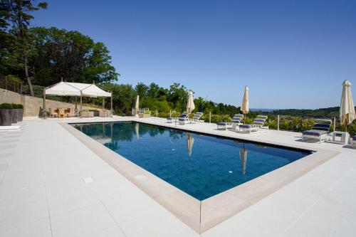 a large swimming pool with chairs and umbrellas at Villa Francesca Relais in Gradara