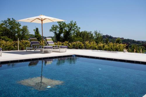 a swimming pool with two chairs and an umbrella at Villa Francesca Relais in Gradara