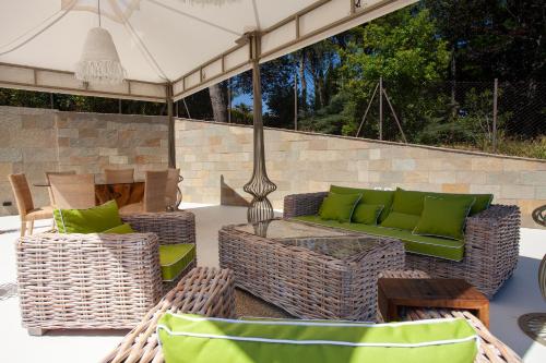 a patio with a green couch and wicker chairs at Villa Francesca Relais in Gradara