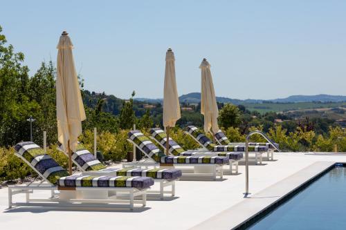 a row of lounge chairs with umbrellas next to a pool at Villa Francesca Relais in Gradara