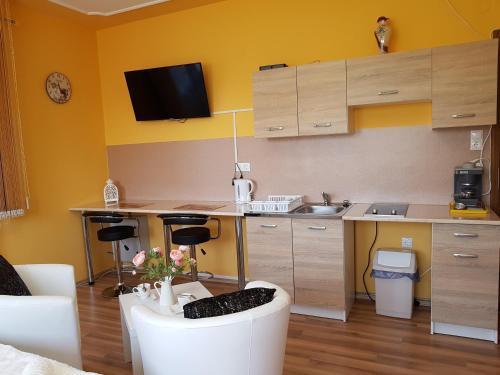 a kitchen with yellow walls and a table with chairs at Mónika Vendégház in Mórahalom