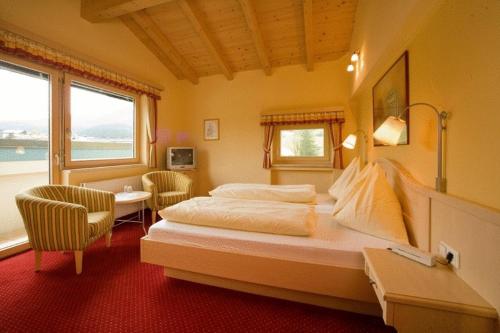 a bedroom with a large bed in a room with windows at Lammertalerhof in Abtenau