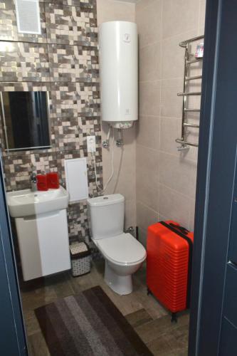 a bathroom with a toilet and a red suitcase at Апартаменты ПРЕМЬЕР in Kamianets-Podilskyi