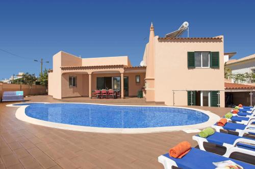 a pool with lounge chairs next to a house at Villa Siroco by Villa Plus in Albufeira