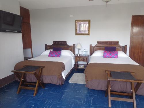 Habitación de hotel con 2 camas y TV de pantalla plana. en Hotel Doña Carmen, en Retalhuleu