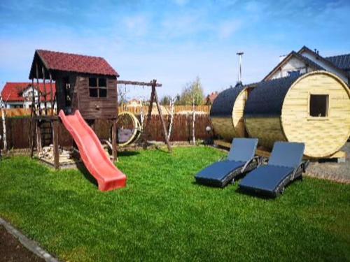 a playground with a slide and two chairs on the grass at Noclegi Mazur przysiersk in Przysiersk