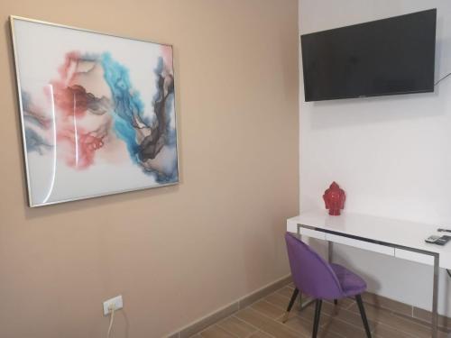a room with a purple chair and a tv on a wall at La Maja Suites in Villahermosa