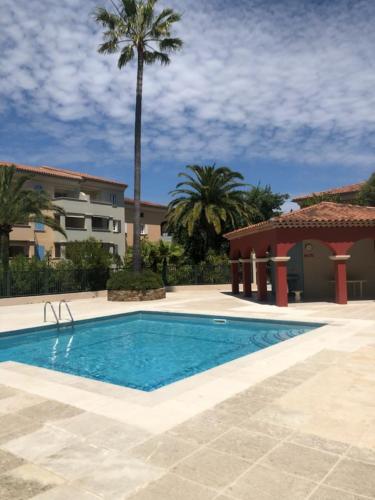 une piscine devant un immeuble avec des palmiers dans l'établissement Belle résidence au centre de Saint Tropez avec piscine et garage, à Saint-Tropez