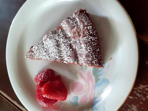 un plato blanco con un trozo de tarta y dos fresas en B&B La vecchia quercia Home Restaurant, en Fornovo di Taro