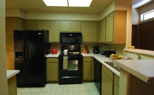 a kitchen with black appliances and green cabinets at Raintree at Phoenix South Mountain Preserve in Phoenix