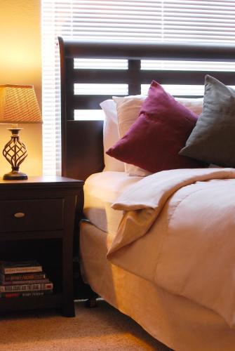 a bed with pillows on it next to a table with a lamp at Raintree at Phoenix South Mountain Preserve in Phoenix