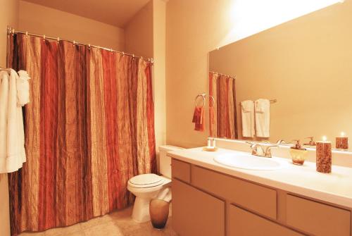 a bathroom with a sink and a toilet and a mirror at Raintree at Phoenix South Mountain Preserve in Phoenix