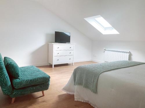 a bedroom with a bed and a chair and a television at Villaprado in Cambados