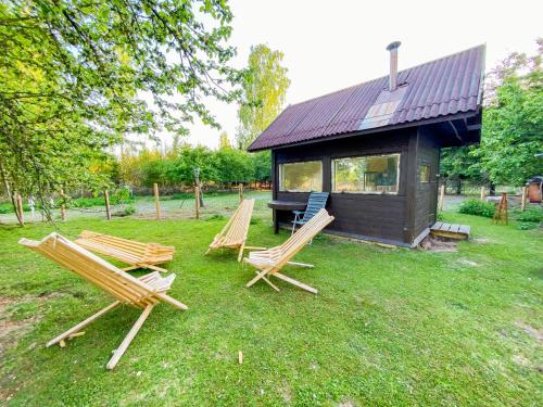 three chairs sitting in the grass in front of a cabin at Private Farm Jakuzzi Sauna in the forest in Talsi