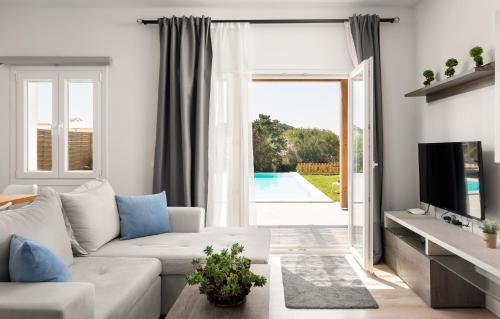 sala de estar con sofá blanco y puerta corredera de cristal en Reiki Villas, en Ereikoússa