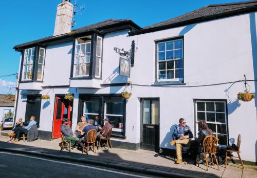 un grupo de personas sentadas fuera de un edificio blanco en Jacobs Ladder Inn en Falmouth