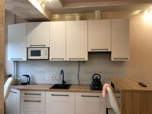 a kitchen with white cabinets and a counter top at Goldenhaus Pushkina str.27 in Vinnytsya