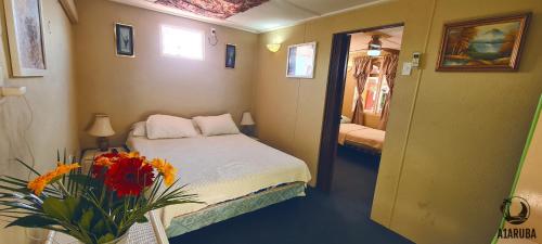 a small room with a bed and a vase of flowers at A1 Apartments Aruba in Oranjestad