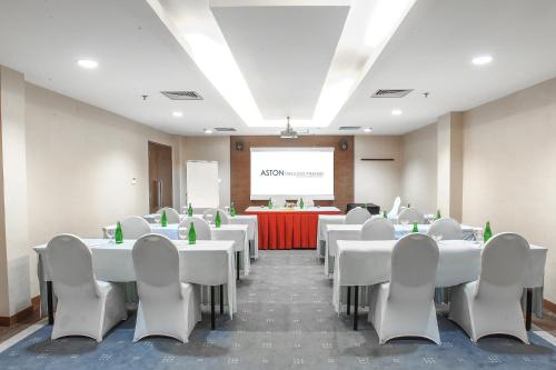 a conference room with white tables and chairs and a screen at Aston Tanjung Pinang Hotel & Conference Center in Tanjung Pinang 