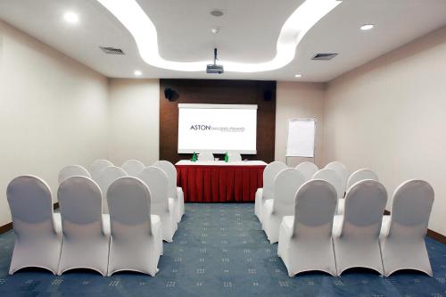 a conference room with white chairs and a screen at Aston Tanjung Pinang Hotel & Conference Center in Tanjung Pinang 