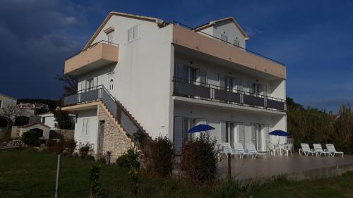 biały budynek z krzesłami i parasolami w obiekcie Apartments Simurina w mieście Vlašići
