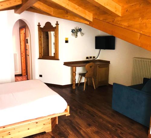 a bedroom with a bed and a desk with a television at Hotel Mountain Resort in Commezzadura