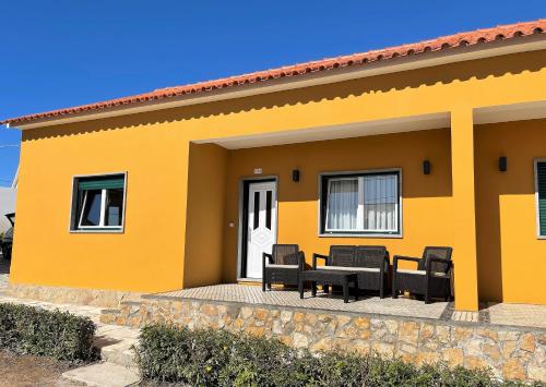 a yellow house with black chairs and a patio at Villa Patrocinio in Ribamar