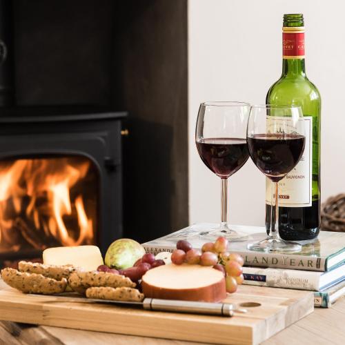 a bottle of wine and two glasses of wine and cheese at Smithy Cottage in Kirkmichael