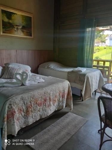 a bedroom with two beds and a table and a window at Recanto Berço das Aguas in Piraquara
